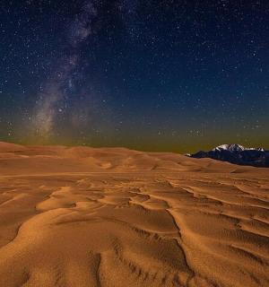 poušť pod noční oblohou plnou hvězd