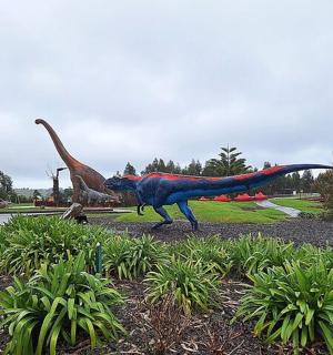 a statue of a dinosaur in a park