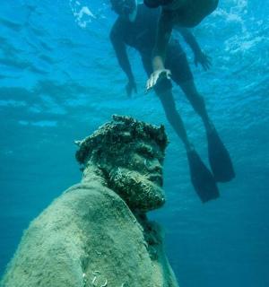 uma pessoa nadando na água ao lado de uma estátua