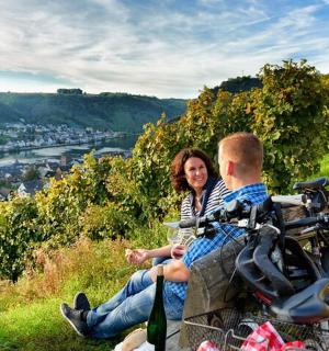 a man and a woman sitting on a hill with a bike