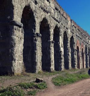两个人沿着建筑物旁边的土路行走