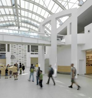 a group of people walking in a library with a glass ceiling