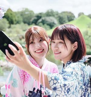 dvě ženy stojící vedle sebe držící mobilní telefon