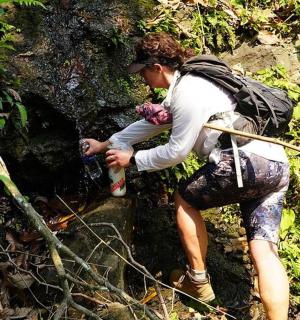 a woman crossing a stream in the forest