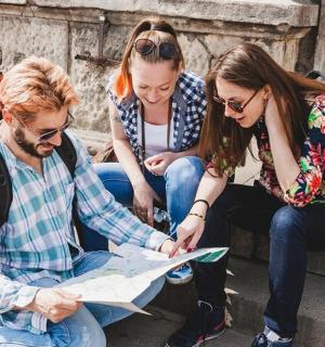 drei Personen sitzen auf einer Treppe und schauen auf eine Karte