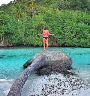a woman standing on top of a rock in the water