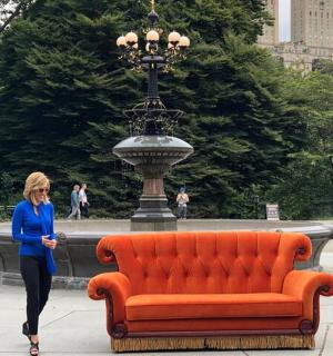 žena procházející kolem oranžové pohovky před fontánou