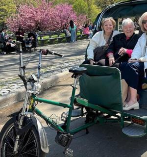 tři ženy sedící v zeleném kočáru s kolem