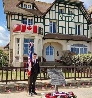 一名男子站在一所房子前，手里拿着一面旗帜