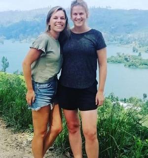 dvě ženy stojící na vrcholu kopce s jezerem