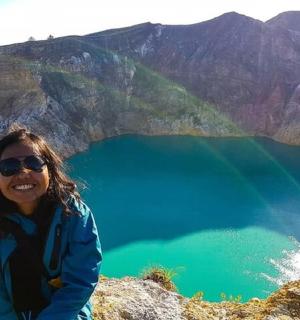 a woman sitting on top of a mountain overlooking a lake