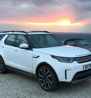 a white car parked next to a car parked next to the ocean