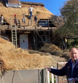 a man standing in front of a building with hay