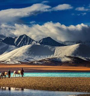 skupina lidí jezdících na koních před horami