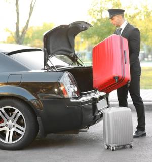 a man in a suit standing next to a car with luggage