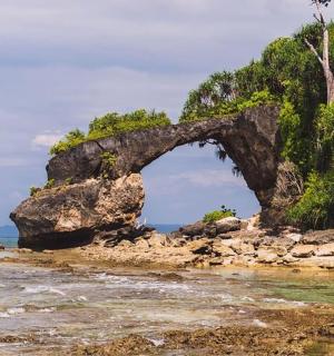 an arch in the rocks on the beach