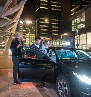 一名男子站在一辆黑色汽车旁边