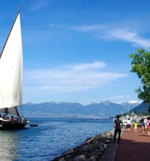 一艘帆船在水中，码头上站着一些人