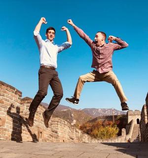 dva muži skákají do vzduchu přes cihlovou zeď