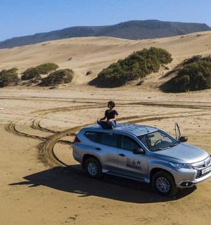 osoba sedící na střeše SUV v poušti