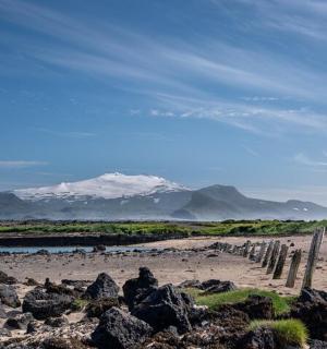 a fence on a beach with mountains in the background