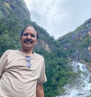 一位老人站在瀑布前