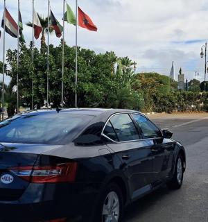 a black car parked in a parking lot with flags