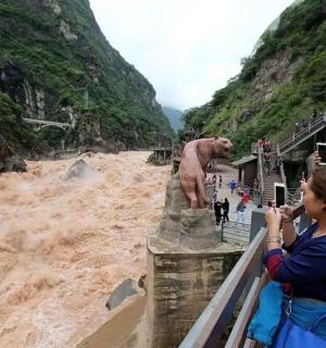 a woman taking a picture of a statue in a river