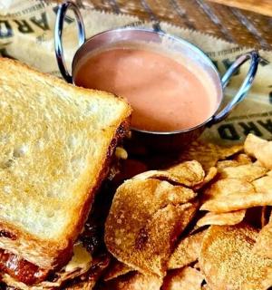 a sandwich and chips and a cup of dipping sauce