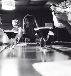 skupina lidí sedících u baru s sklenicemi na víno