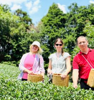 a group of three people standing in a tea plantation