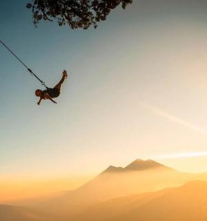 一名男子在山上的绳索秋千上