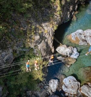 a group of people crossing a suspension bridge over a river