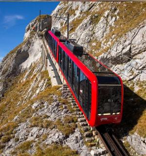 a red train on the tracks on a mountain