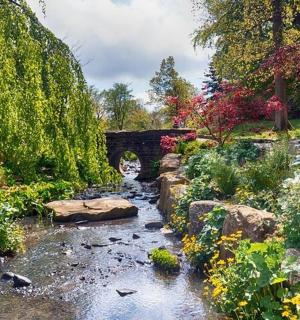 eine Brücke über einen Bach in einem Garten
