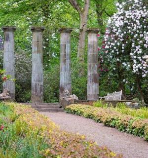 ein Garten mit einer Bank und Blumen und Bäumen