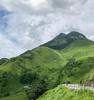 a green mountain with a road in front of it