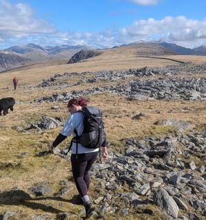一名背着背包在岩石山上行走的女子