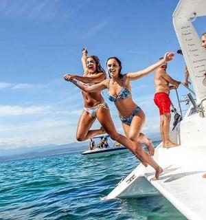 a group of women jumping off of a boat