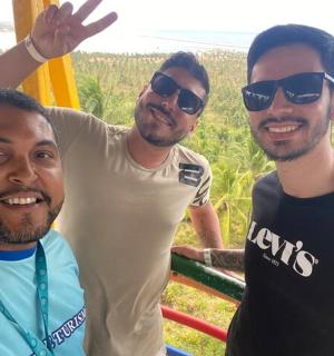 three men are posing for a picture on the beach