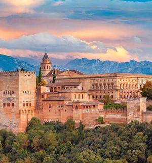 um grande castelo em uma colina com montanhas ao fundo