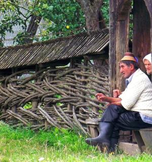 一名男子坐在木栅栏旁的长椅上