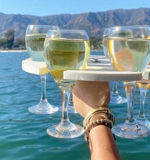 four glasses of wine on a tray on the water