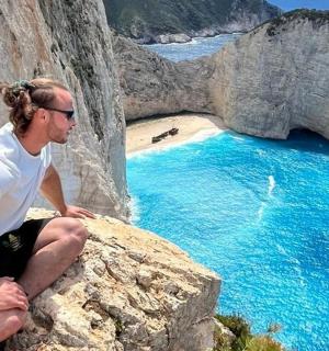 mężczyzna siedzący na skale obok plaży