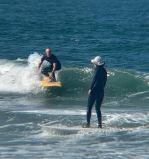 dva muži jedoucí na vlně na surfových prknech v oceánu
