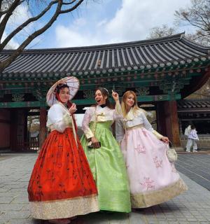 三个穿着裙子的女孩站在一栋建筑前