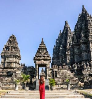 a woman in a red dress standing in front of a temple