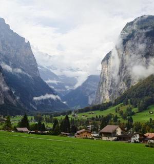 μια ορεινή κοιλάδα με ένα χωριό σε ένα καταπράσινο χωράφι
