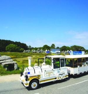 a small bus driving down the road near a field