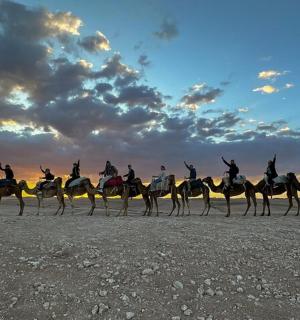 eine Gruppe von Menschen reitet auf Kamelen am Strand